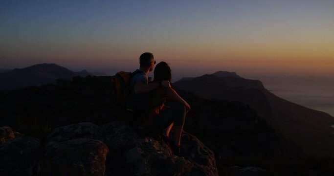 Couple, hiking and summit for adventure, night and mountain top over ocean, standing and silhouette. Fitness, exercise and climbing with backpack, dark or view for man, woman or backpacker in nature