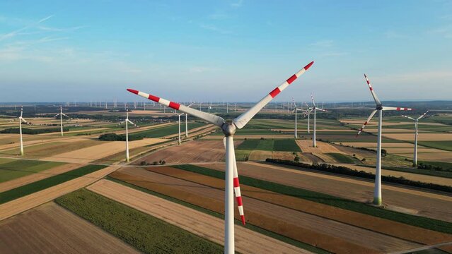 Wind power turbines generating clean renewable energy for sustainable development. Windmills Turbine in Austria, large orange sun disc summer lens flare. Alternative energy