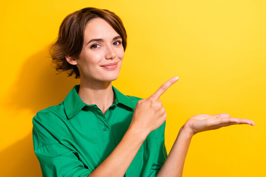 Photo of cute sweet girl dressed green shirt showing arm pointing finger empty space isolated yellow color background