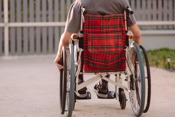 Obraz premium A young man with disabilities in relax time on beauty nature background,Lifestyle with disability person in the garden or park with safe wheel chair access, Concept of facilities for wheelchair users.