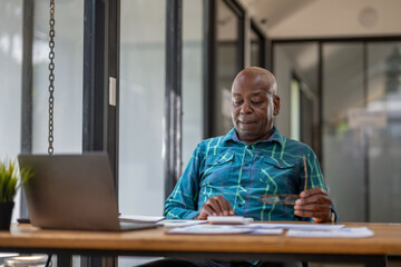Senior black man looking at laptop. Consider the work ahead. Thinking about work project ideas