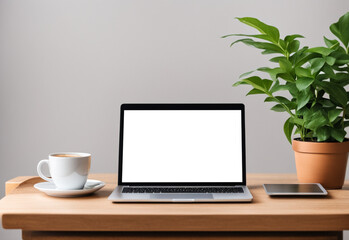 Fototapeta premium a mockup with a laptop with an empty space standing on a table with a cup of coffee and a tablet. on the background is a simple minimalistic background decorated with a plant