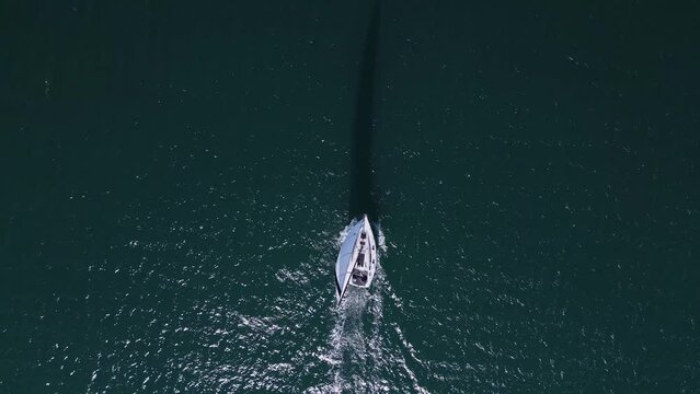 A yacht with all sails set races across the sea, propelled by the wind. Aerial view