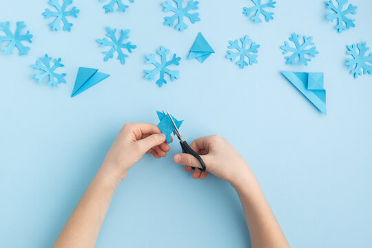 Hands Making Paper Snowflakes On Blue Child Hands