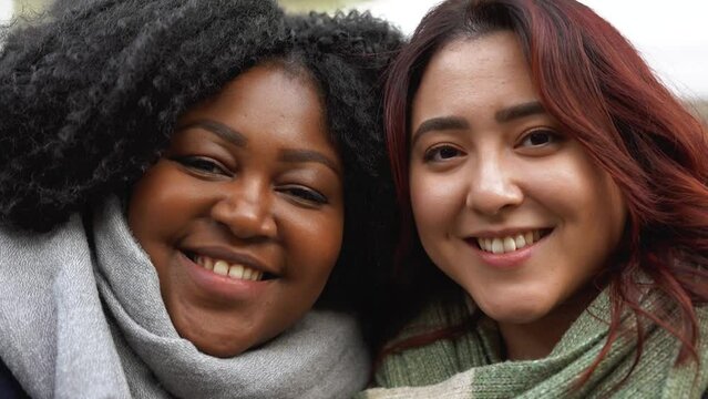 Young multiracial women looking on camera outdoor during winter time - Concept of diversity and friendship	