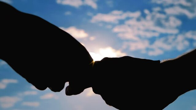 One person is giving a bribe to another person. Woman is counting dollar bills. Hands silhouettes with money, banknotes against the sunset, sunrise sky - close up view, sun lens flares