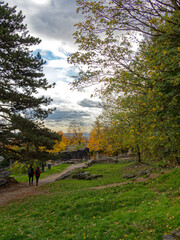 Fall colors in Lugdunum archeological park and roman theater, distant couple walks hand in hand in the ruins, Lyon France