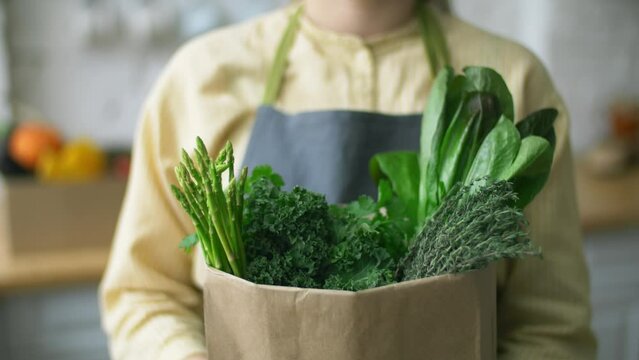 fresh green vegetables and herbs in a paper bag. zero waste shopping concept - groceries in paper bag. online shopping, grocery delivery. fresh produce from local markets