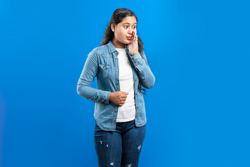Image of a charming pretty smart clever Indian girl sharing good news silently over blue background