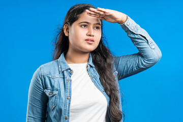 Indian young women watching far away with hand over eyes