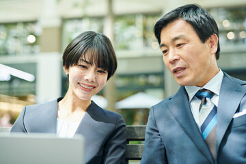 ベンチで話をする50代男性会社員と30代女性会社員