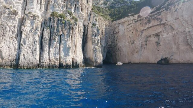 Anchored sailboats in turquise blue by near large sea caves in paxos island greece, slow motion