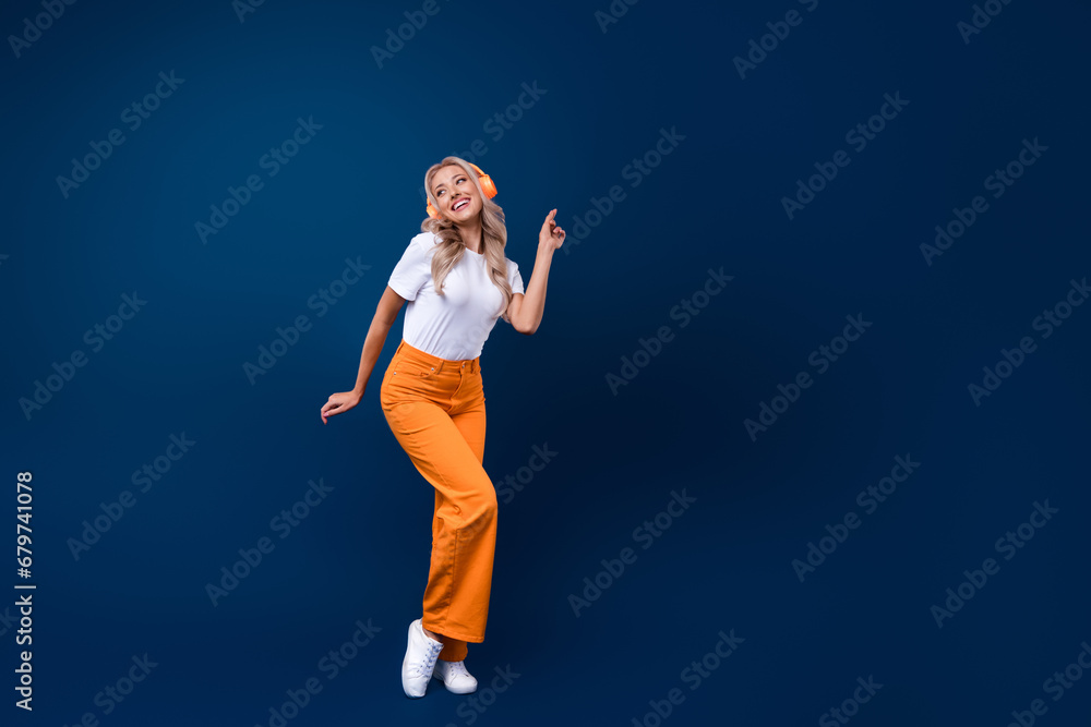 Poster Full length photo of cheerful glad girl dressed trendy clothes dancing looking empty space banner isolated on dark blue color background