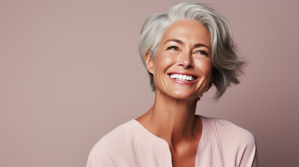 Charming mature 50s woman with gray hair smiling and looking aside isolated on plain pink background. Healthy lifestyle concept