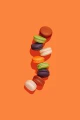 Poster french dessert macarons, different colors on orange textureless background top view purple, green, white, orange, pink © Kateryna