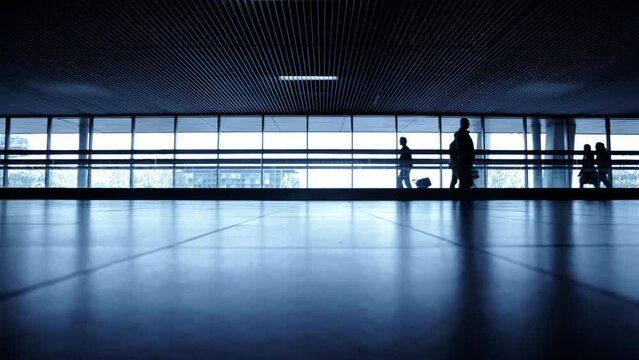 Traveler silhouettes with moving walkway at airport hall 