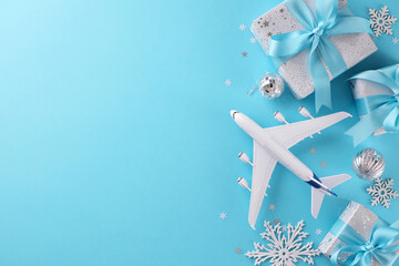 Concept of a Christmas vacation. Top view flat lay of gift boxes, yule tree ornaments, miniature plane, snowflakes, stars on blue background with promo zone - obrazy, fototapety, plakaty