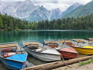 Rowing boats waiting for tourists to rent at the emerals lake of the Lago Inferiore di Fusine in the Julian alps in the North of Italy close to the border with Slovenia
 - obrazy, fototapety, plakaty