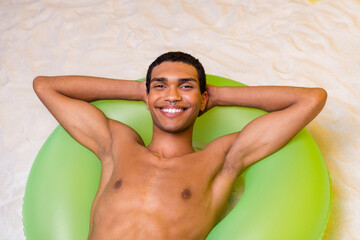 Photo of good mood attractive shirtless man lying inflatable circle sun bathing arms behind head...