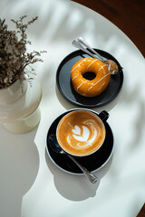 Hot coffee latte with latte art milk foam in cup mug and Homemade Orange Donut wood desk on wood...