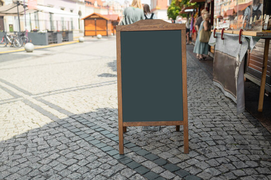 Wooden rustic blackboard in front of restaurant entrance. Mock up menu blank blackboard sign stand shop cafe restaurant. High quality photo