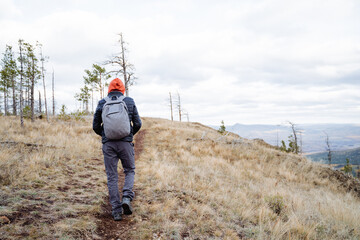The man is wearing a warm jacket and pants that protect him from the cold and wind. On his feet he wears special boots for mountain hiking, and on his back is a backpack with the necessary things.
