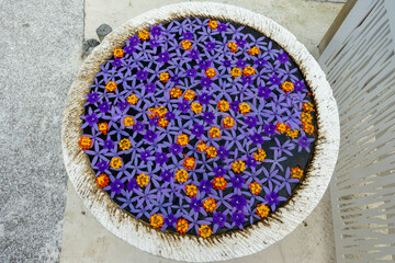 Top view of a flower mandala with purple and orange petals floating on water in a vase, tropical floral decor, Seychelles