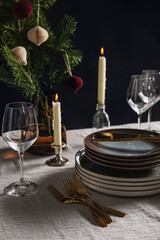 winter holidays, dinner party and celebration concept - crockery and candles for scandinavian christmas table serving over black background
