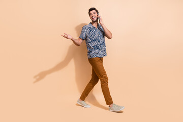 Full length photo of young man talking people making a phone call looks for information empty space isolated on beige color background