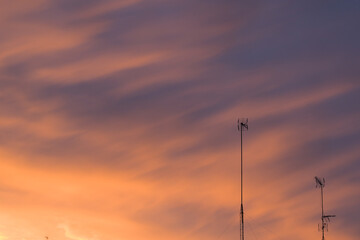 Television antennas over red cloudy sky during sunset