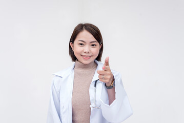 Portrait of a young and skilled doctor, medical student, intern, posing while pointing at the camera. Isolated on a white background.