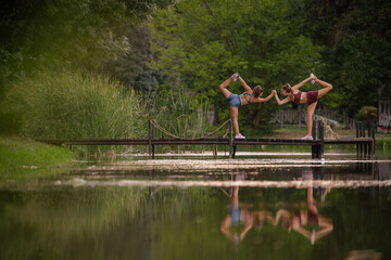 Fit females warm up in a park, stretching and preparing for their evening workout on a bridge.
