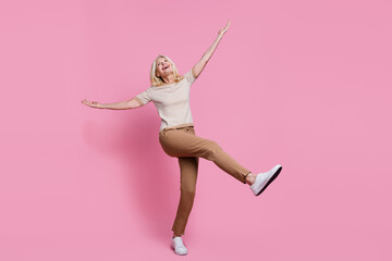 Full length portrait of overjoyed cheerful person raise hands dancing partying isolated on pink...