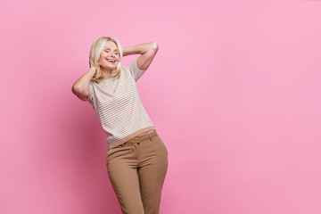 Portrait of overjoyed satisfied woman wear trendy clothes hands on head touching hair eyes closed isolated on pink color background