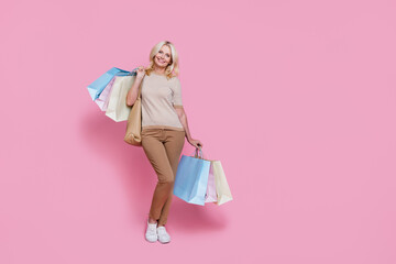 Full length photo of charming cute lady dressed stylish clothes hold packs seasonal price empty space isolated on pink color background