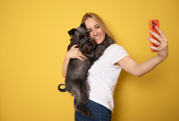 Friendship concept. Happy european woman taking selfie with her cute schnauzer dog, looking and...