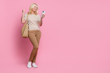 Fototapeta na wymiar Full size portrait of attractive person use smart phone raise fist accomplish success empty space isolated on pink color background