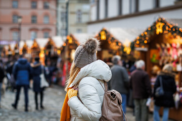 Woman is enjoying the Christmas market in city during the Advent holiday - obrazy, fototapety, plakaty