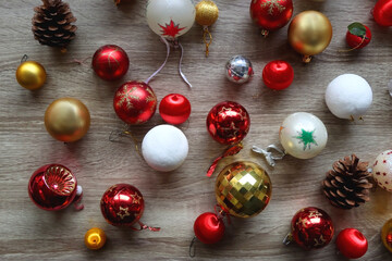 Pine cones and red, golden and white Christmas ornaments on wooden background. Top view.