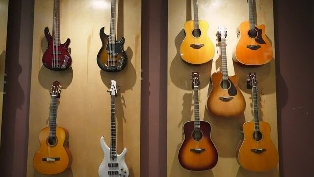 Electric and classical wooden acoustic guitars hanging on the showcase wall in a musical instrument store