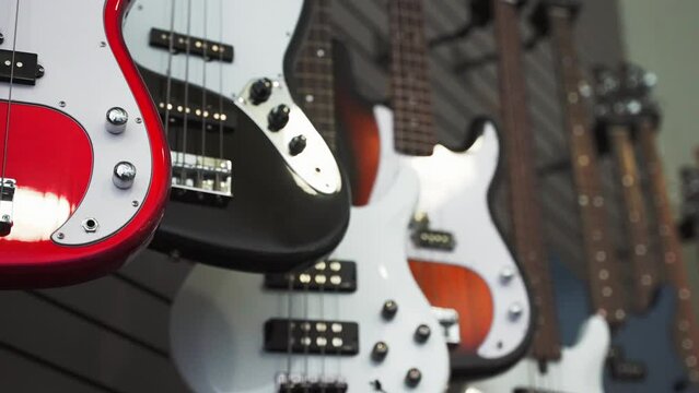 Close up rack focus of electric acoustic guitars hanging on the showcase wall in a musical instrument store