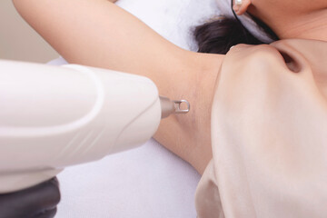 A young woman undergoes an underarm laser whitening treatment session at an aesthetic clinic.