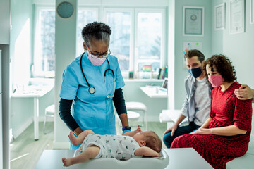 Pediatrician giving a newborn baby a medical exam with the babys parents in the office