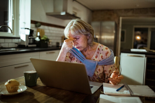 Stressed senior woman working from home on laptop looking worried