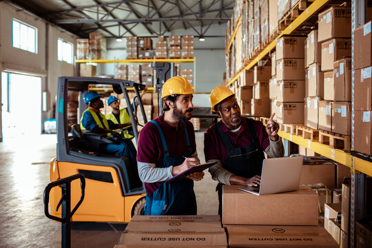 Male warehouse workers doing inventory writing on clipboard