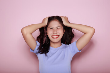 Portrait of a beautiful young woman in a light pink background, happy and smile, posting in stand...