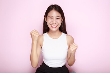 Portrait of a beautiful young woman in a light pink background, The Asian woman was acting very cheerful, Beautiful girl smiling happily.