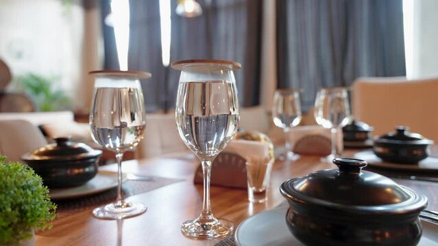 Close up of restaurant table served with glasses of water and black ceramic soup pots