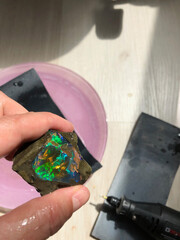 Polishing a rough opal with sandpaper and a rotary tool