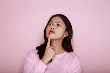 Fototapeta premium Asian woman making a stressed expression Standing alone on a light pink background. Beautiful young woman is feeling stressed.